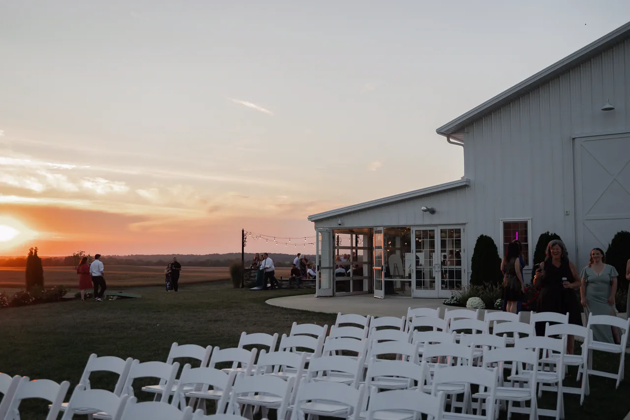 Wedding guests outside a barn venue at sunset